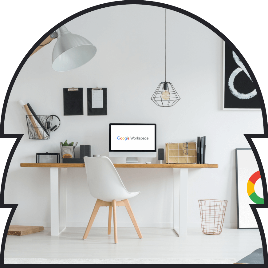 A desk space of a Google Workspace end user. With a monitor, chair, lamp, and books.