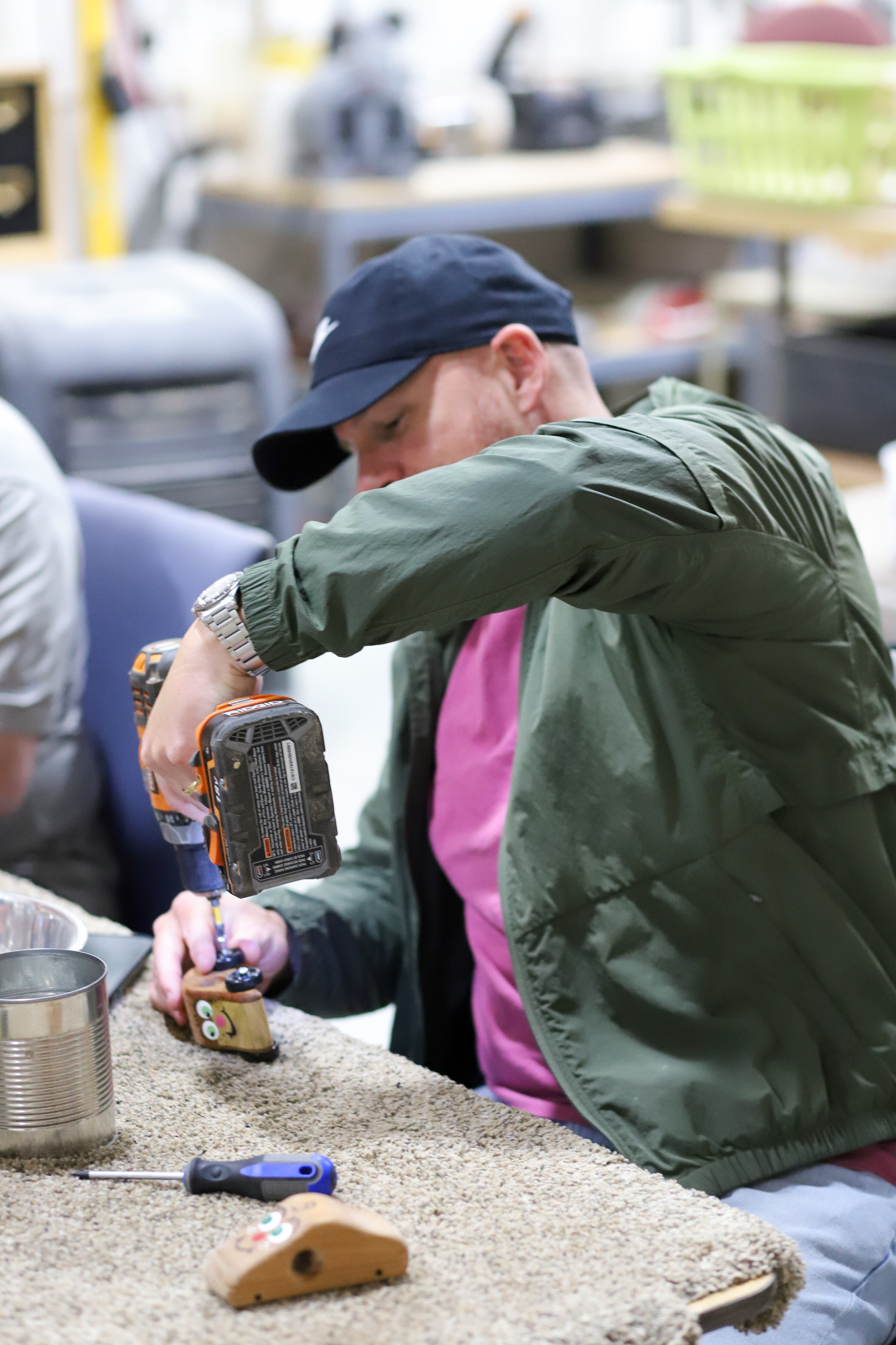 A BrainStorm Employee sitting at a table using a tool to work on a toy car.